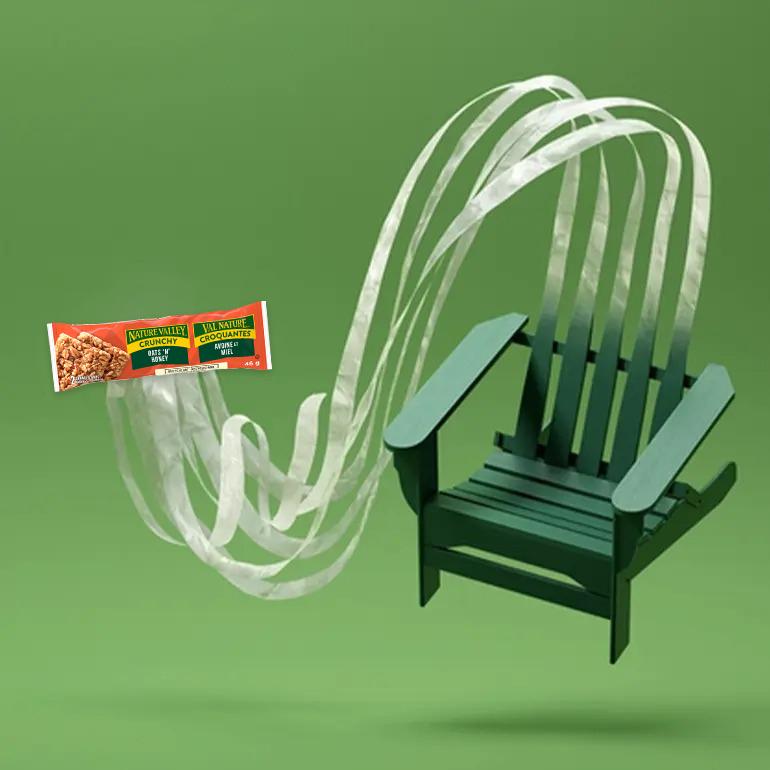 Une barre Nature Valley Crunchy Oats 'N' Honey avec des rubans en plastique sortant de l'emballage et se fondant dans l'image d'une chaise en plastique.